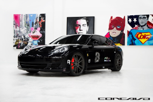 Ein schwarzer Nissan-Sportwagen mit Cartoon-Plakaten im Hintergrund und einer kleinen Inschrift unten.