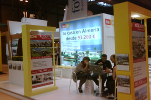 Eine Gruppe von Menschen sitzt an einem Tisch und schaut auf einen Laptop, mit mehreren Flyern, auf denen verschiedene Werbeanzeigen zu sehen sind.