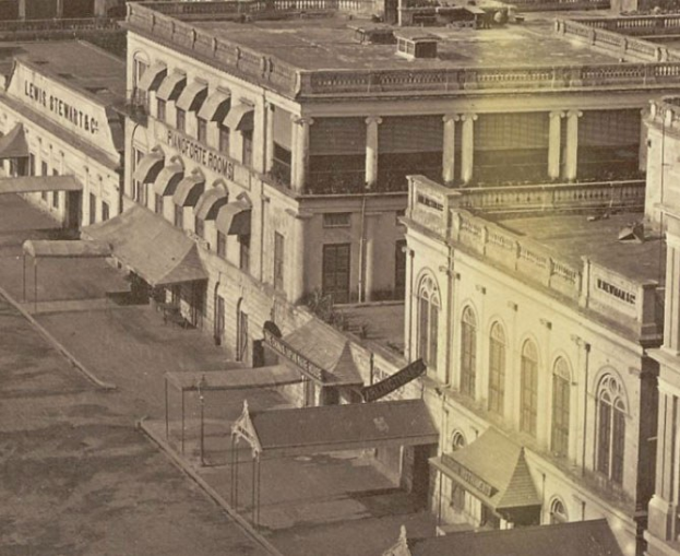 Altes Schwarz-Wei├č-Foto einer Stadtstra├če mit Geb├Ąuden, Fenstern, S├Ąulen, Namensschildern, Schuppen und Masten.