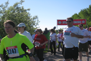 Eine Gruppe von Kindern läuft bei einem Marathon, mit einer roten Fahne und Bäumen im Hintergrund.