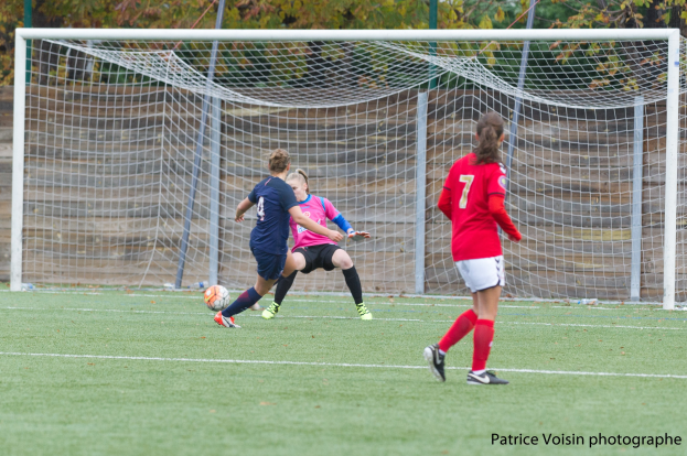 Gruppe von Frauen, die Fußball auf einem grünen Rasenfeld mit Bäumen im Hintergrund und einem Torpfosten spielen, mit Text unten.