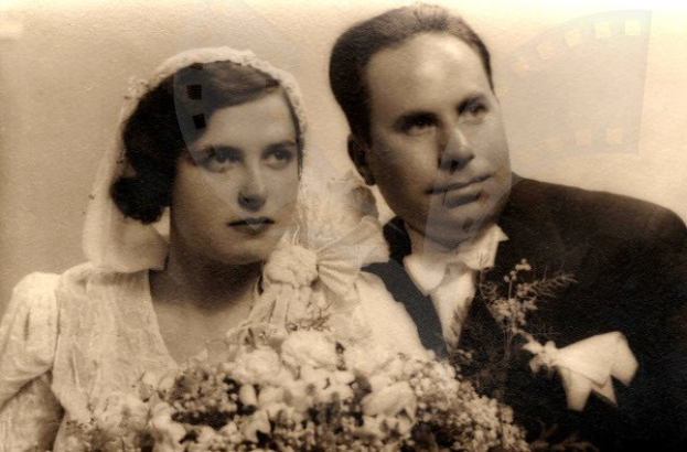 Schwarz-weißes Foto eines lachenden Mannes und einer Frau, die zusammenstehen, die Frau in einem weißen Kleid mit einem Strauß Blumen.