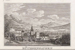 Eine Gravur eines Schlosses in Büchisenhausen, Deutschland, eingebettet in eine Gebirgskette mit Bäumen und Hügeln, unter einem bewölkten Himmel, mit Text am unteren Bildrand.