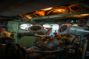 Das Innere eines Zuges mit Sitzen und verschiedenen Gegenständen, eine Person auf der linken Seite in einem gelben T-Shirt.