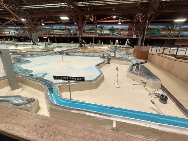 Ein großes Indoor-Wasserpark mit zahlreichen Wasserrutschen, Pfosten, Texttafeln, Deckenleuchten und Wandgemälden, entworfen als Minigolfplatz für einen spaßigen und aufregenden Erlebnis.
