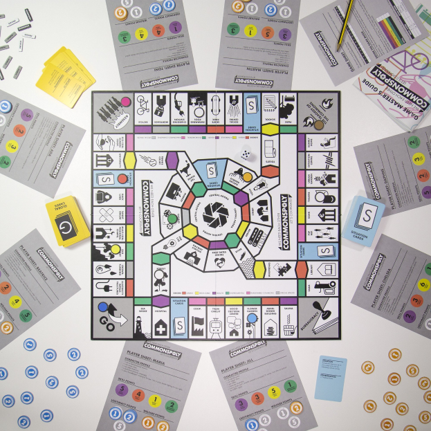 Ein Monopoly-Brettspiel auf einem Tisch mit verstreuten Karten, Papieren und einem Bleistift darum herum.