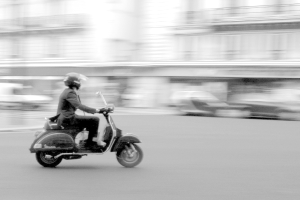 Eine Person, die ein Roller auf einer Straße fährt.