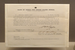 Ein Blatt Papier mit dem Text "Eid für Bundesrichter" darauf, das auf einem Tisch vor einer Wand liegt.