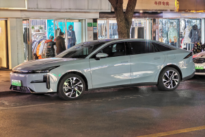 Ein Mitsubishi Lancer EV-Elektroauto, das nachts auf einer Straße geparkt ist, umgeben von Gebäuden, Geschäften, Schaufensterpuppen, Schildern und Lichtern.