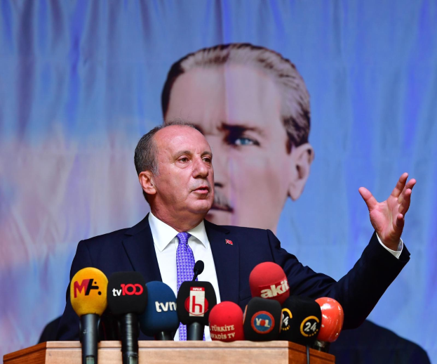 Ein Mann im Anzug steht an einem Podium mit Mikrofonen und spricht hinter einem Bildschirm, wahrscheinlich zu der Ankündigung des Rücktritts von türkischen Präsident Recep Tayyip Erdogan.