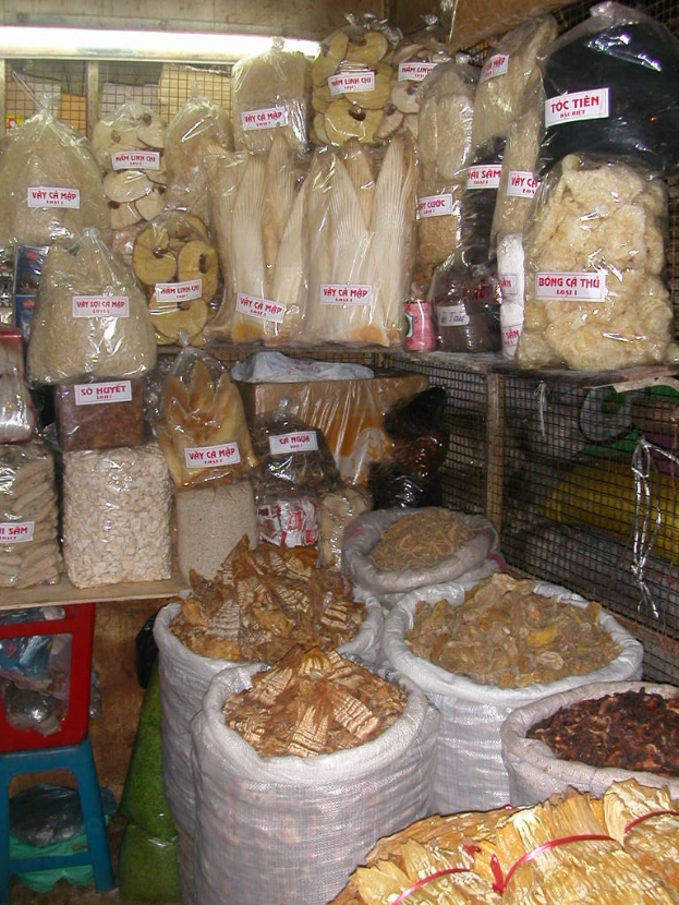 Ein Marktstand mit ordentlich sortierten Lebensmitteln in Tüten und Plastikabdeckungen auf Gestellen, die gut sortiert und organisiert wirken.