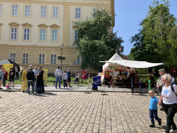 Eine Gruppe von Menschen geht eine Kopfsteinpflasterstraße in Krakau, Polen, entlang mit Zelten, Tischen und einem Gebäude mit sichtbarem Text im Hintergrund.