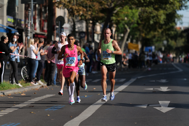 Gruppe von Läufern bei einem Marathon auf einer Stadtstraße mit Zuschauern und unscharfem städtischem Hintergrund.