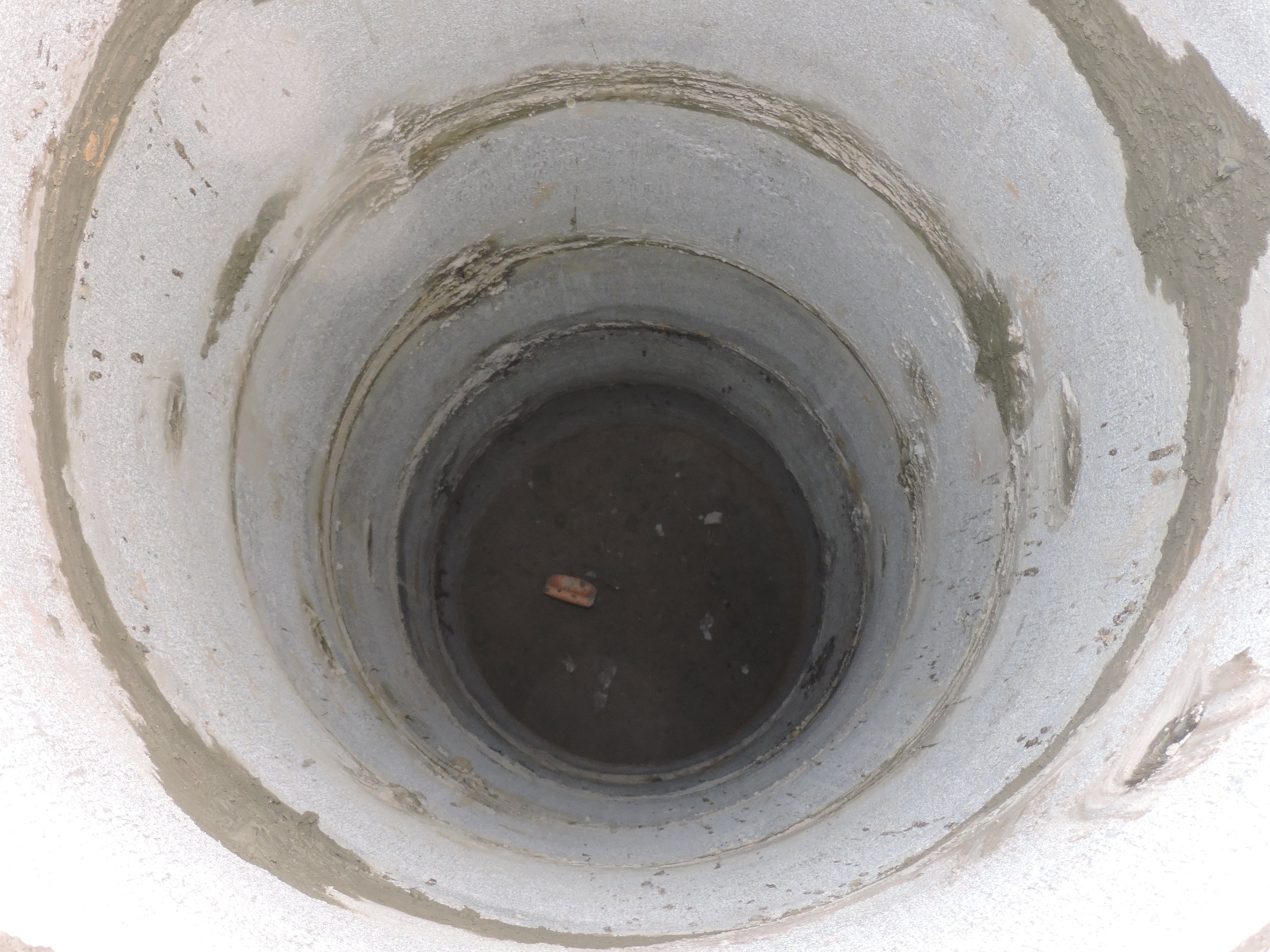 Betonsielrohr mit einer zentralen Bohrung in einer Betonwand, das ein Objekt enthält.