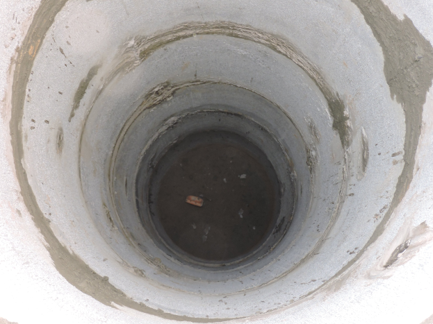 Betonsielrohr mit einer zentralen Bohrung in einer Betonwand, das ein Objekt enthält.