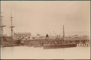 Eine Szene mit Wasser, Booten, Gebäuden, Strommasten und einem Himmel.