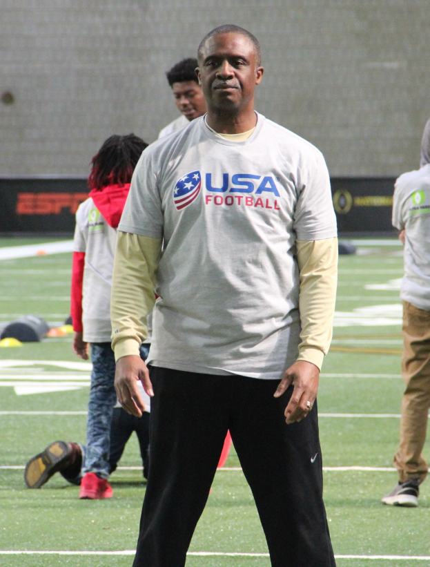 Ein Fußballspieler auf einem Feld mit Zuschauern und einer Wand im Hintergrund.