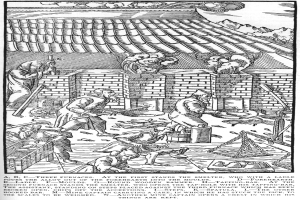 Eine Schwarz-Weiß-Zeichnung einer Gruppe von Menschen, die in einer Fabrik arbeiten, mit einem Haus im Hintergrund und einem Text unten, der "A.B.C. Three Furnaces at the First Stands the Smelter" lautet.