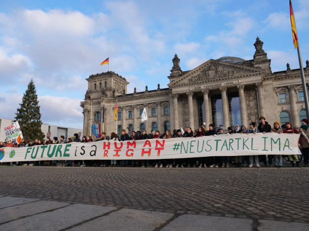 Gruppe von Menschen vor dem Reichstagsgebäude in Berlin mit einem Transparent, auf dem "Zukunft ist ein Menschenrecht" steht
