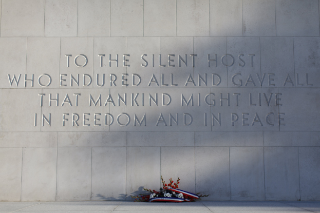 Gedenkwand mit der Inschrift "Dem stillen Gast, der alles ertrug und alles gab, damit die Menschheit in Freiheit und Frieden leben möge" umgeben von einem Blumenstrauß.