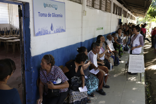 Menschen, die auf Bänken vor einem Gebäude sitzen und darauf warten, an einer Wahllokal in Guadalajara, Mexiko, zu wählen.