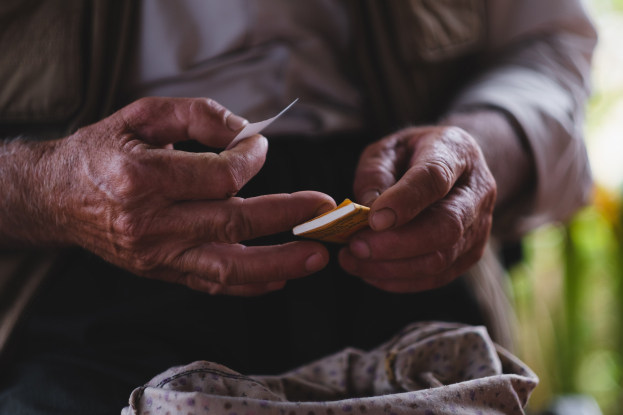 Alter Mann hält ein Stück Papier und sieht besorgt aus, mit einem unscharfen Hintergrund, wahrscheinlich aufgrund von Demenz.