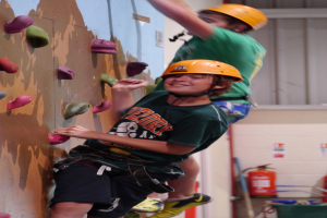 Eine Person klettert an einer Wand hoch, neben ihr ein Feuerlöscher.