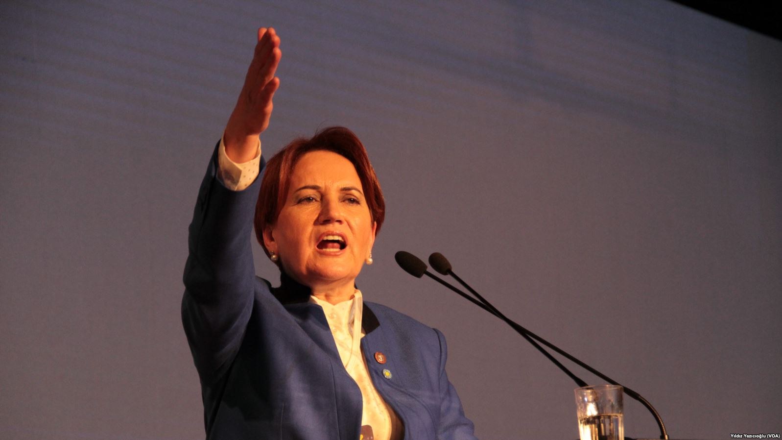 Frau, die an einem Podium mit zwei Mikrofonen und einem Glas Wasser steht und vor einem Bildschirm spricht, wahrscheinlich eine Rede im Zusammenhang mit einem Regierungsverbot von Frauenrechten hält.