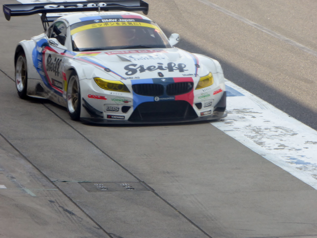 Ein strahlend blau-weißer BMW Z4 GT3 Rennauto mit großen glänzenden Rädern auf einer Rennstrecke, mit einer schlanken aerodynamischen Gestaltung und einem prominenten BMW-Logo.
