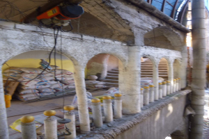 Altes Gebäude mit Bogengang, Säulen und Treppen wird renoviert, mit verstreuten Werkzeugen, Materialien und Gegenständen, darunter Taschen und eine Maschine mit Drähten oben drauf.