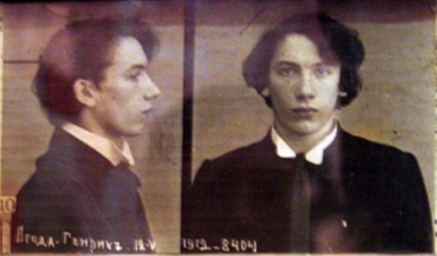 Ein Mugshot eines Mannes in einem schwarzen Anzug, weißem Hemd und schwarzer Krawatte mit ernstem Gesichtsausdruck und zurückgekämmten Haaren, begleitet von zwei weiteren Fotos und fetter Schrift, die seine Verbrechen beschreibt.