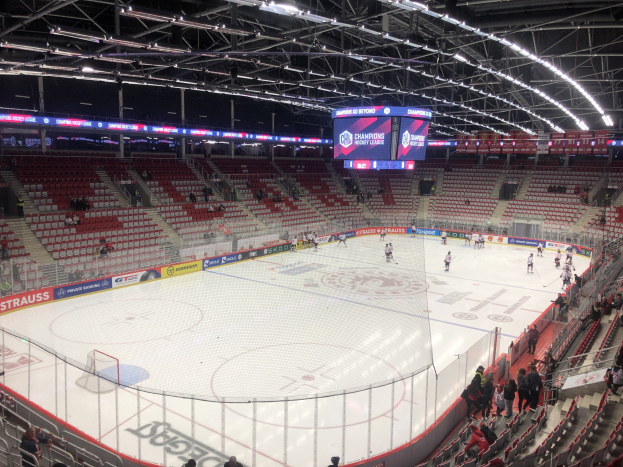 Eishockeyspiel in einer großen Arena zwischen den St. Louis Blues und Detroit Red Wings, mit Zuschauern auf den Sitzen und Stehplätzen in der Nähe der Eisfläche umgeben von einem Zaun und einem Display.