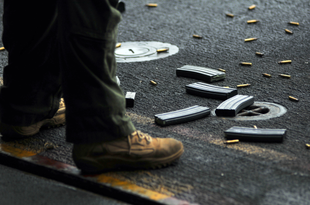 Ein Mann steht neben einem Haufen Magazine auf der Straße und trägt Schuhe.